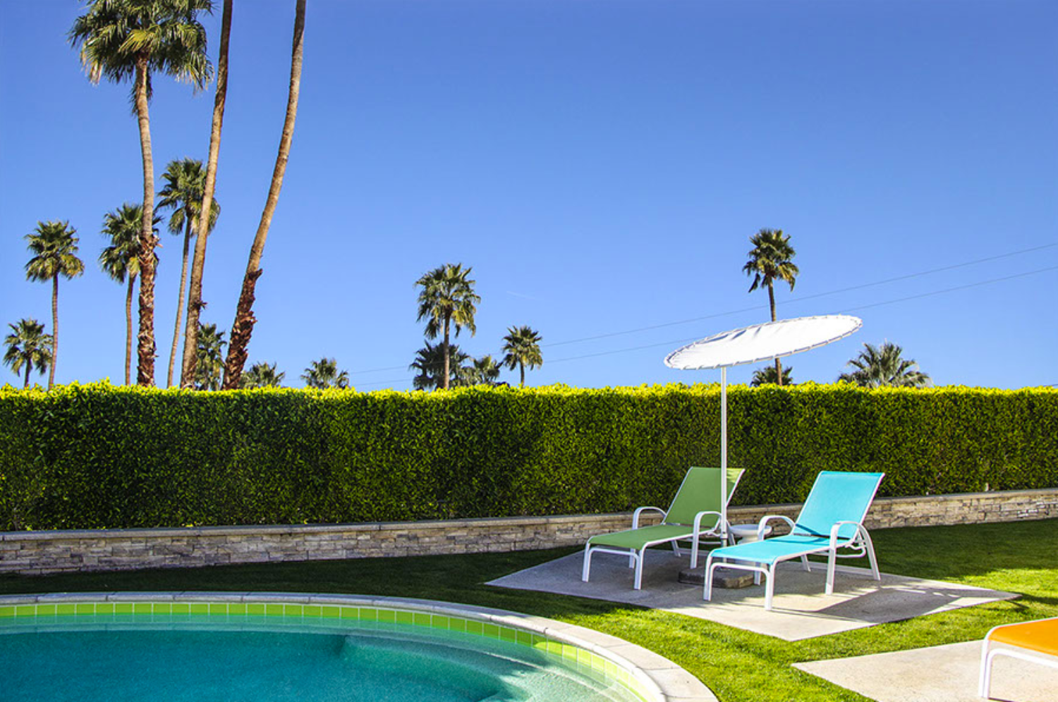 bright palm springs art print with sun bathing chairs by the pool